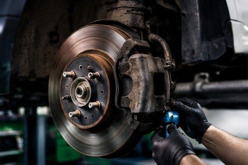 Brake disc and caliper being replaced on a lifted vehicle